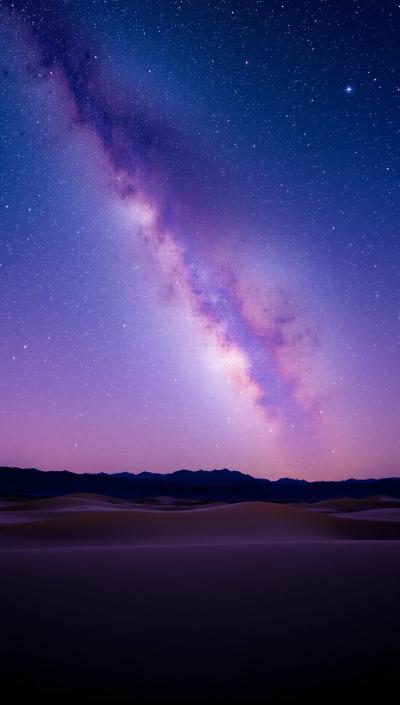 Milky Way galaxy over a serene desert landscape at night, star trails, purple and blue sky